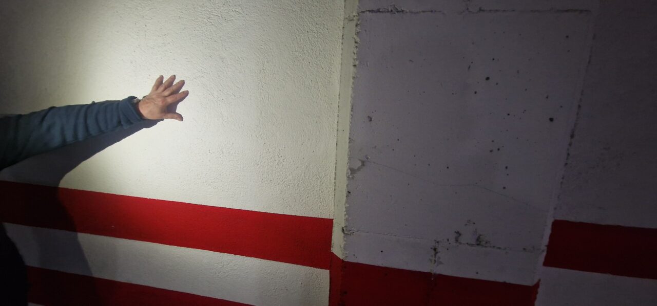 Instalador señalando el trazado de la canalización del cargador en la pared de un garaje comunitario