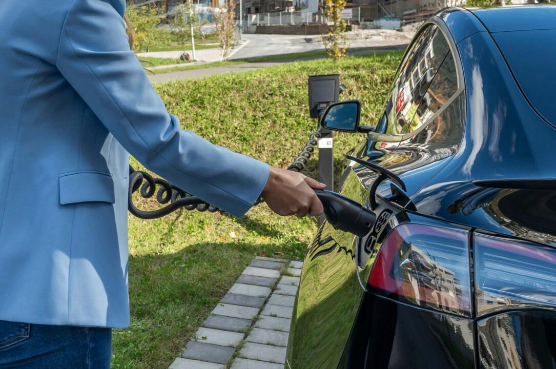 Persona enchufando un vehículo eléctrico en un punto de recarga público