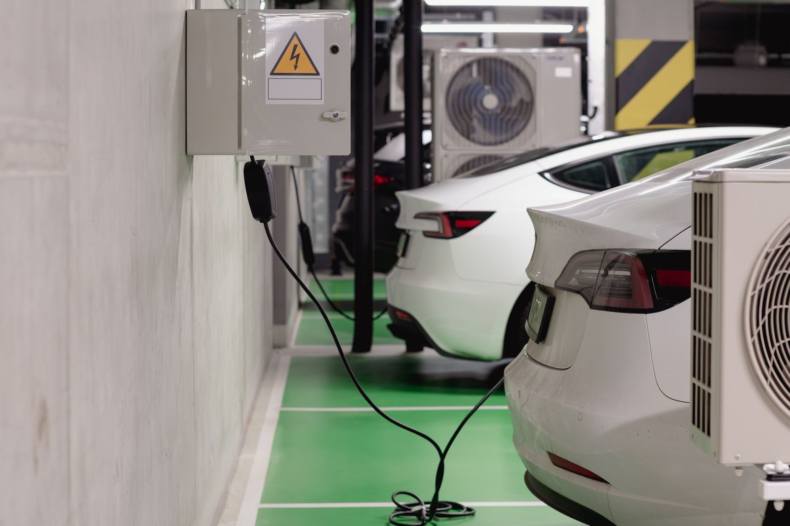 Varios coches eléctricos cargando simultáneamente en puntos de recarga de pared en un garaje subterráneo